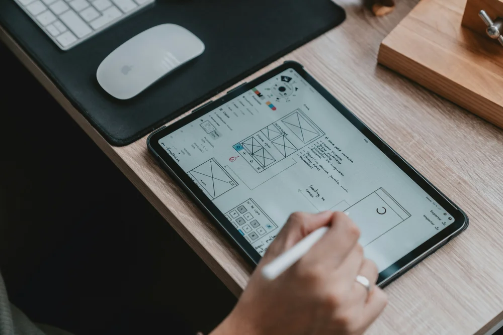 Person sketching website wireframes on a tablet with stylus at a clean workspace